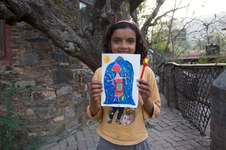 A girl holding up her blue alien, Rishikesh